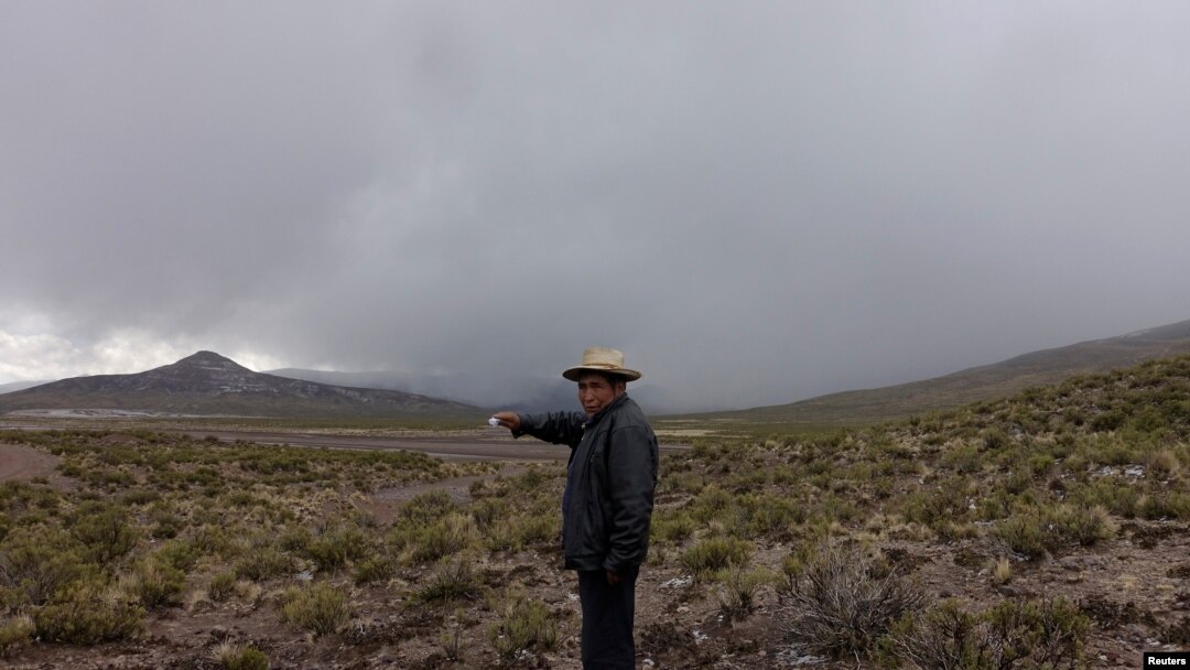 Un hombre señala una nube de ceniza del volcán Ubinas, en Santiago de Machaca, Bolivia, a lo largo de la frontera con Perú, el 20 de julio de 2019.