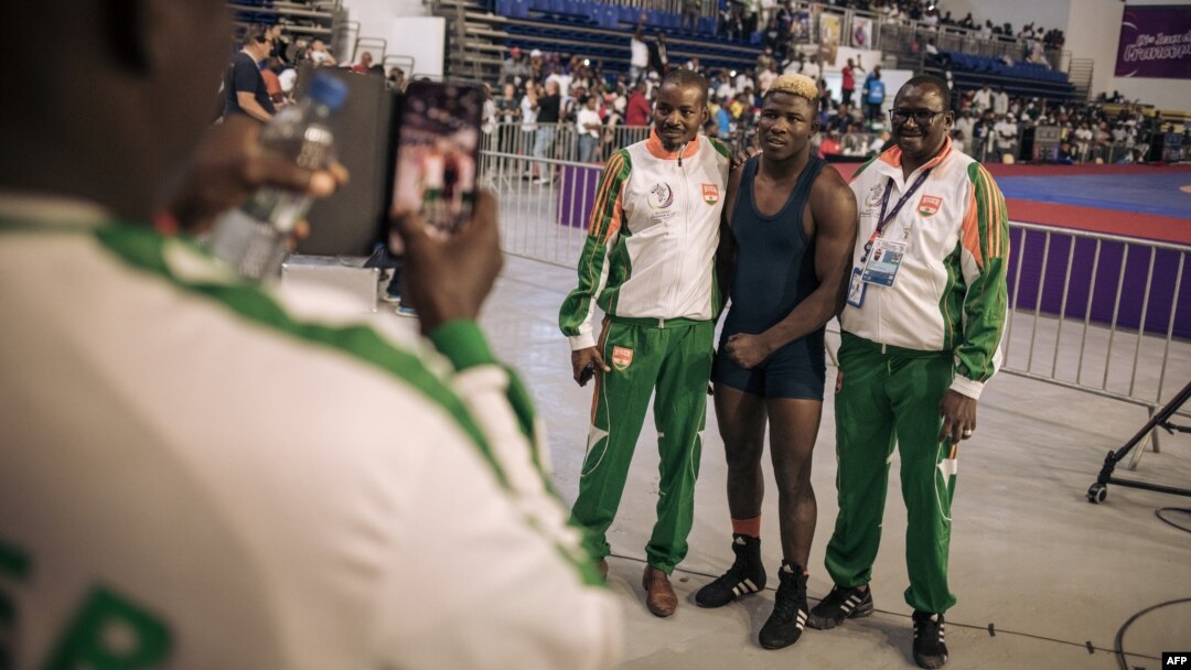 Niger delegation members pose with one of their wrestlers, center, who won a bout at the 9th Francophone Games in Kinshasa, July 30, 2023. Because of the July 26 military coup in Niamey, some members of the Niger delegation were unable to reach Kinshasa.