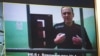A screen shows jailed Kremlin critic Alexey Navalny as he arrives to listen to a hearing on an appeal lodged against a court decision to jail him for 19 years in a maximum security prison on extremism-linked charges, at a court in Moscow.