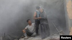 Palestinians react at the site of an Israeli strike on a house, amid the Israel-Hamas conflict, in Deir Al-Balah, in the central Gaza Strip.
