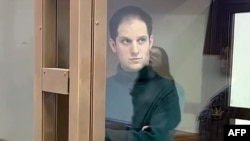 Jornalista americano Evan Gershkovich dentro de uma compartimento de vidro num tribunal de Moscovo