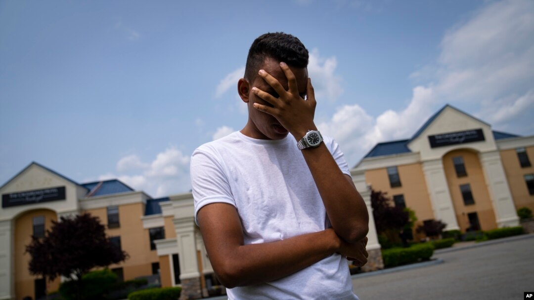 Mohamed, a 19-year-old fleeing political persecution in Mauritania, poses for a photo that obscures his face to protect his identity, outside the Crossroads Hotel, before heading into town for a work opportunity, May 22, 2023, in Newburgh, N.Y. 