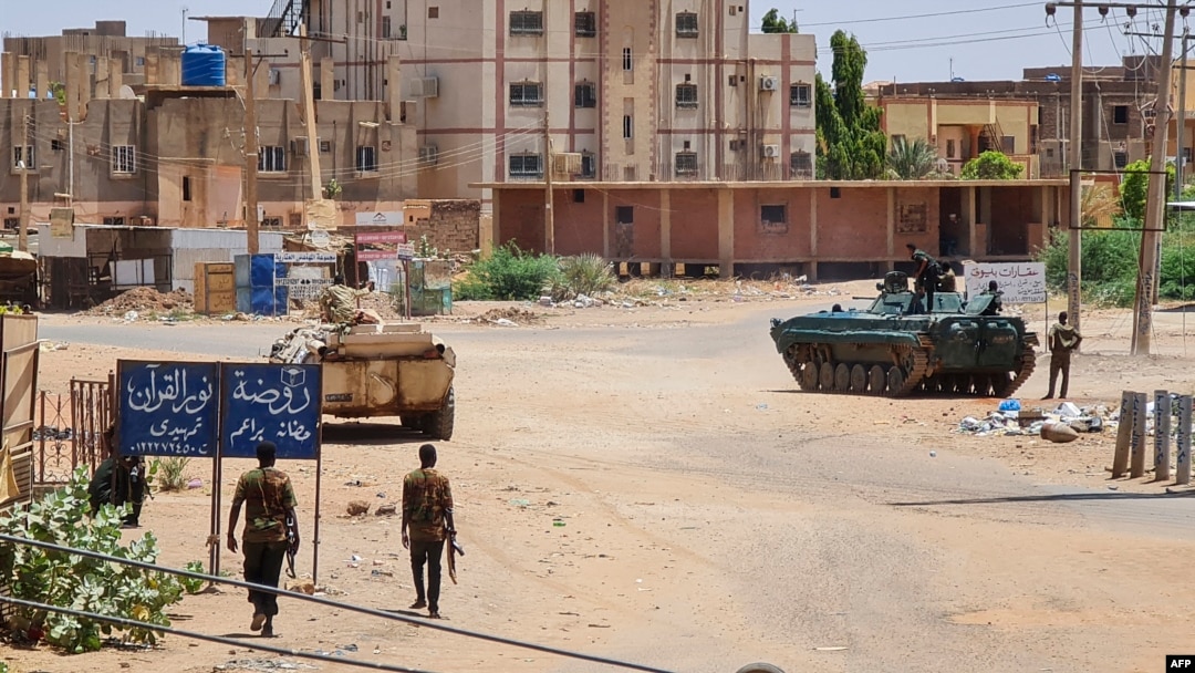 Sudanese Army soldiers walk near armored vehicles positioned on a street in southern Khartoum, May 6, 2023, amid ongoing fighting between the Army and the paramilitary Rapid Support Forces.
