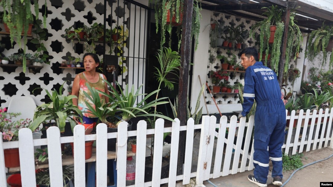 Un trabajador del Ministerio de Salud habla con un residente de un asentamiento antes de rociar insecticida para prevenir el dengue en Lima, Perú, 7 de marzo de 2024.