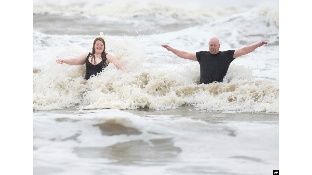 Jeremy Reddout y su hija, Elexus, disfrutan de las olas entre Murdoch's y Pleasure Pier mientras llueve en Galveston, Texas, el 19 de junio de 2024.