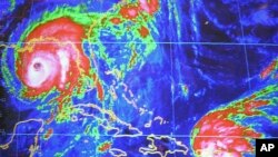 FILE - Hurricane Ivan seen on the computer screen at the National Hurricane Center in Miami, Wednesday, Sept. 15, 2004, seen 250 miles from the Gulf Coast, and Tropical Storm Jeanne is seen as it approaches Puerto Rico.