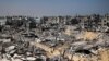 FILE - People walk amid the rubble of destroyed buildings in Khan Yunis, Gaza Strip, on April 16, 2024. Rubble throughout Gaza is probably contaminated with unexploded ordnance, say landmine and explosives experts at a U.N. conference in Geneva on May 1, 2024.