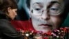 FILE - A woman places flowers before a portrait of slain Russian journalist Anna Politkovskaya in Moscow on Oct. 7, 2009.