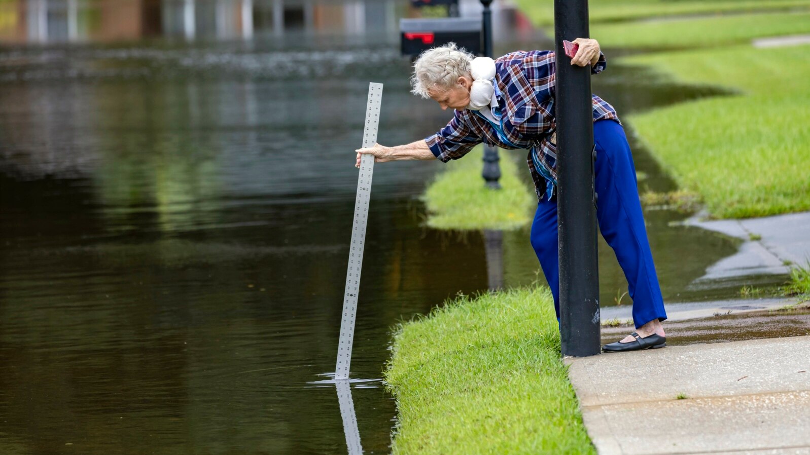 A resident measures the depth of stormwater in a flooded street in Pooler, Georgia, Aug. 7, 2024. 