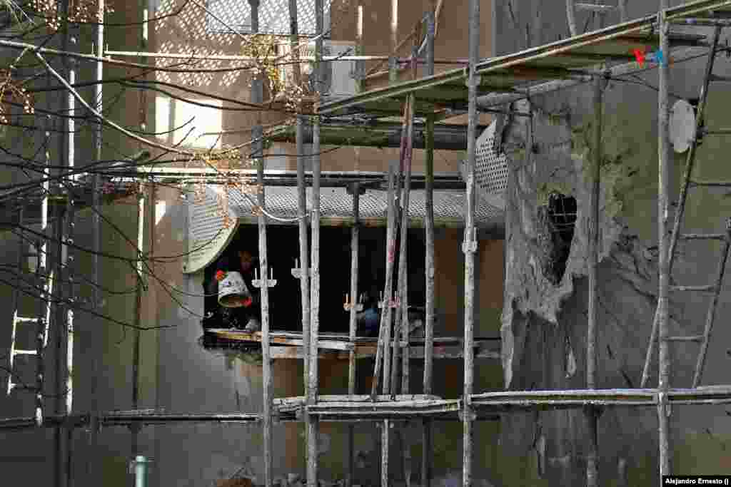 Obreros palestinos de ciudades vecinas trabajan en la reconstrucción de edificios impactados por los cohetes disparados desde Gaza.