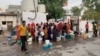 As taps in their homes run dry during the summer, people fill water for their daily use from an overhead tank. (Anjana Pasricha/VOA)
