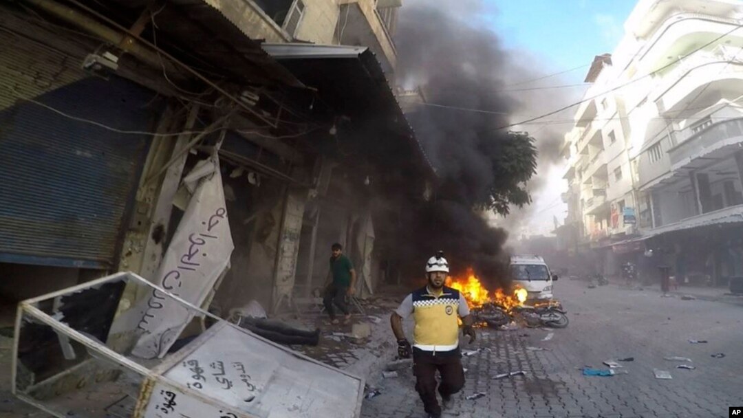 In this photo provided by the Syrian Civil Defense White Helmets, a Syrian White Helmet civil defense worker runs at the site where a shell struck in the outskirts of the northern town of Jisr al-Shoughour, west of the city of Idlib, Syria, Oct. 5, 2023. 