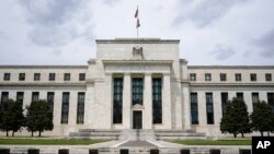 FILE - An American flag flies over the Federal Reserve building in Washington, May 4, 2021.