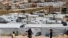 FILE - Syrian refugee children play at an informal refugee camp, which is seen set between the houses and buildings in Arsal, near the border with Syria, east Lebanon, June 13, 2018.