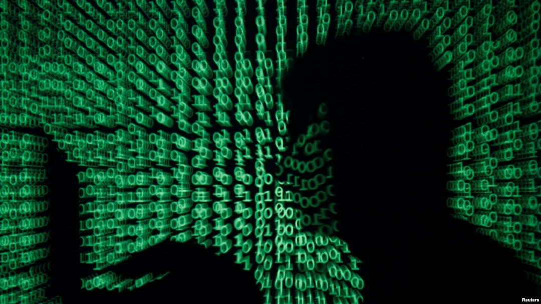 FILE - A man holds a laptop computer as cyber code is projected on him in this illustration picture taken on May 13, 2017.