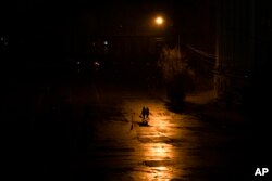People walk across a street during a blackout in Kyiv, Ukraine, Nov. 6, 2022.