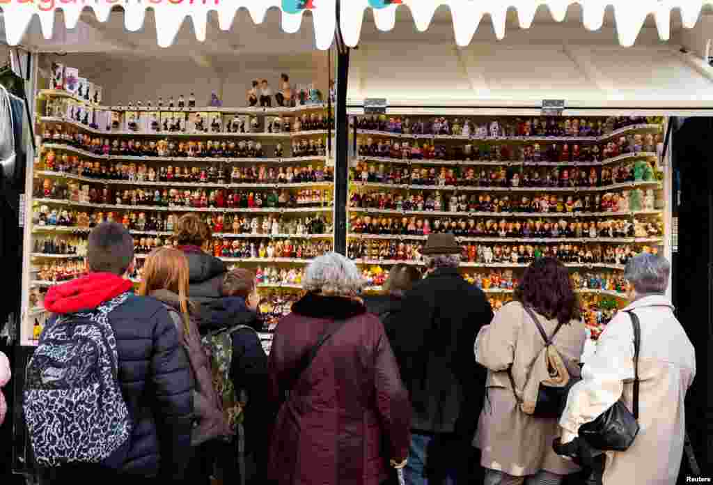 En la Feria de Navidad de Santa Lucía, en Barcelona, personas se acercan a mirar figurillas de "caganers", uno de los elementos más tradicionales de los pesebres en la zona de Cataluña, en el noreste de España.