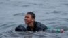 FILE - Achraf, 16, cries as he swims using bottles as floaters, near the fence between the Spanish-Moroccan border, after thousands of migrants swam across the border, in Ceuta, Spain, May 19, 2021. 