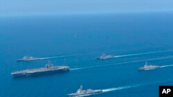 资料照:这张由日本海上自卫队提供的照片显示,2022年4月12日,在日本海举行的美日双边演习中,林肯号航母(左)和金刚号护卫舰(前)编队航行。(美联社)