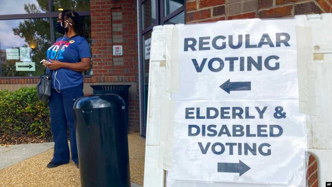 FILE - Signs showing the way for voters stand outside a Cobb County voting building during the first day of early voting, Oct. 17, 2022, in Marietta, Ga.