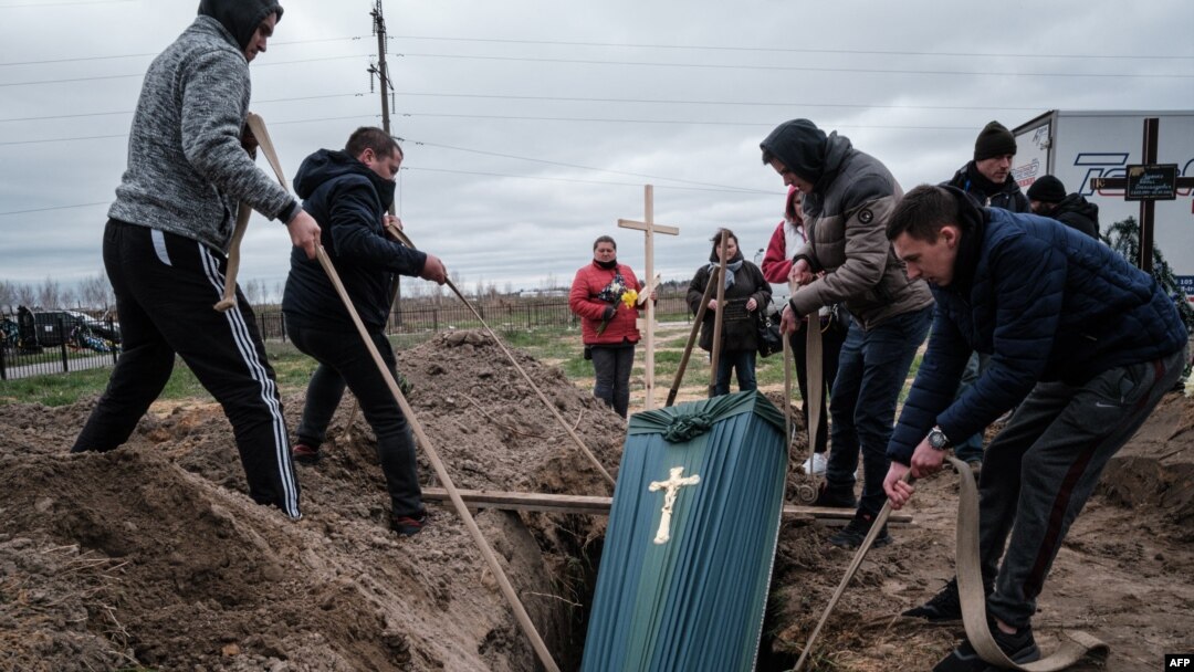 Los familiares de Mykhailo Romaniuk, de 58 años, asesinado a tiros en su bicicleta el 6 de marzo, ayudan a enterrar su ataúd en un cementerio de Bucha, el 19 de abril de 2022, durante la invasión rusa de Ucrania. 