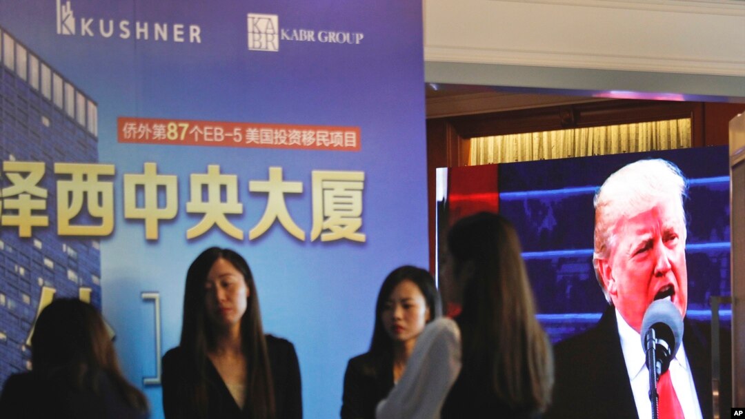 A projector screen shows a footage of U.S. President Donald Trump as workers wait for investors at a reception desk during an event promoting EB-5 investment in a Kushner Companies development at a hotel in Shanghai, China, May 7, 2017. 