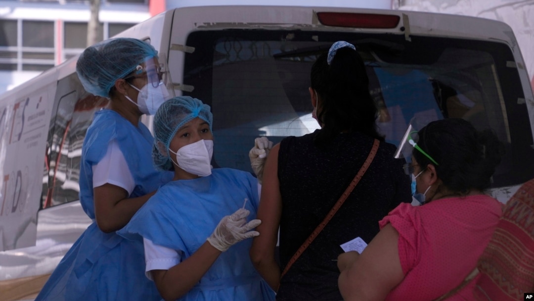 Trabajadores de la salud inoculan a mujeres con la vacuna AstraZeneca COVID-19, afuera del estadio de fútbol Rommel Fernández, en Ciudad de Panamá.