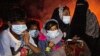 FILE - Ethnic Rohingya women and children sit by a fire on a beach after their boat was stranded on Idaman Island in East Aceh, Indonesia, June 4, 2021, after leaving a refugee camp in Bangladesh.