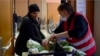 Zohra, left, who did not give her last name, packs up free food from the Salvation Army in Paris into her cart. Like many Europeans, she is having a hard time making ends meet. 