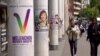 People pass campaign posters for far-left candidate Sarah Legrain and Jean-Luc Melenchon, leader of the France Unbowed party, who wants to become France's next prime minister. (Lisa Bryant/VOA)