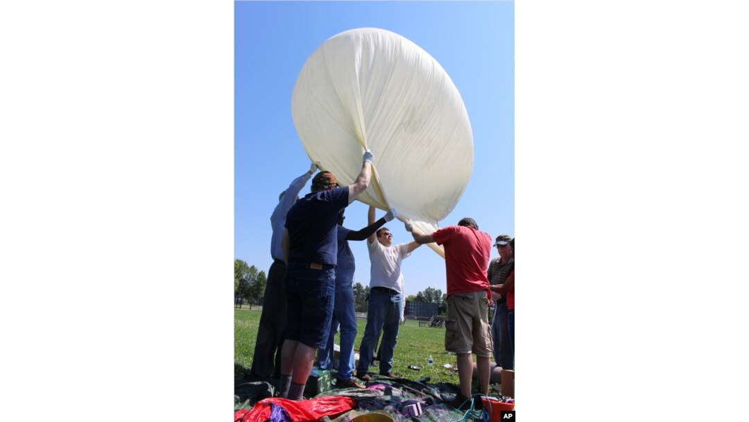 Students and faculty, including Mark Iewicz, center, a mechanical engineering student, prepare to test launch a camera-carrying balloon at the University of Hartford in West Hartford, Connecticut, Aug. 9, 2017.