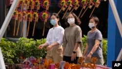 在中國北京街頭戴著口罩的婦女經過一個擺放風車玩具的攤位（2022年9月13日）。