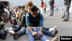 FILE - Migrants rest after disembarking from the British assault ship HMS Bulwark at the Sicilian port of Catania after being rescued at sea, Italy, June 8, 2015.