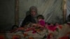 Reda Abu Zarada wraps herself and her grandchildren in blankets as they prepare to sleep in their tent at a camp in Khan Younis, Gaza Strip, Dec. 19, 2024. 