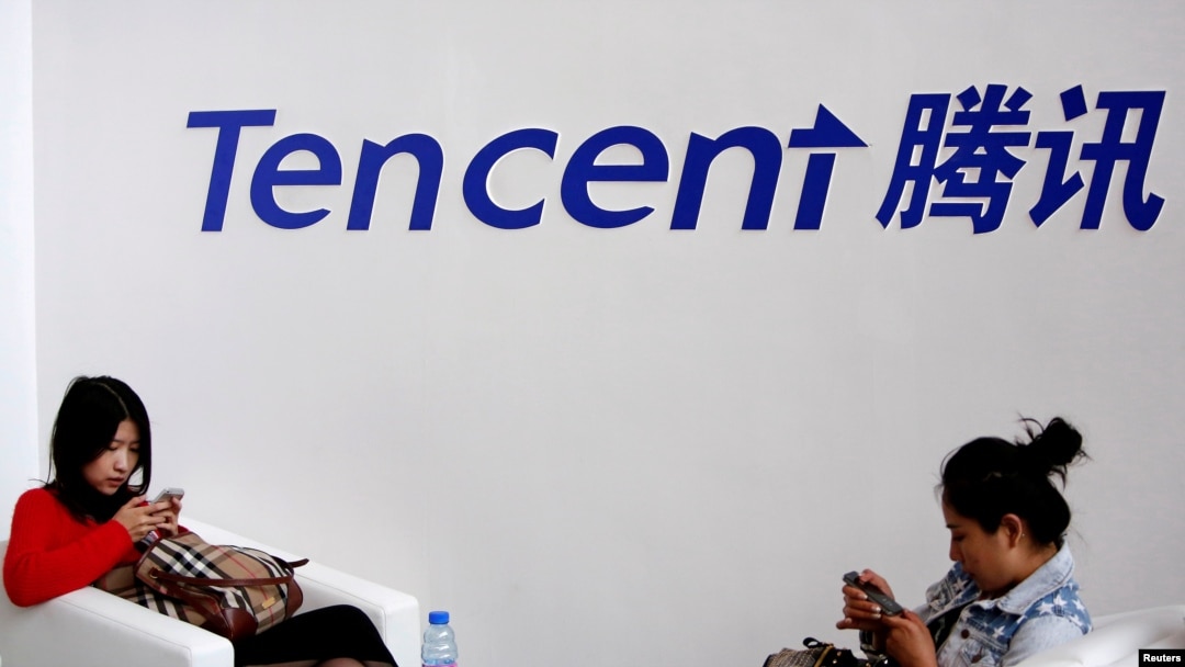 FILE - Visitors use their smartphones underneath the logo of Tencent at the Global Mobile Internet Conference in Beijing, May 6, 2014. 