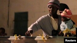 Uma mulher zimbabueana acompanhada de filho, exercendo o direito de voto nas eleições gerais da semana passada