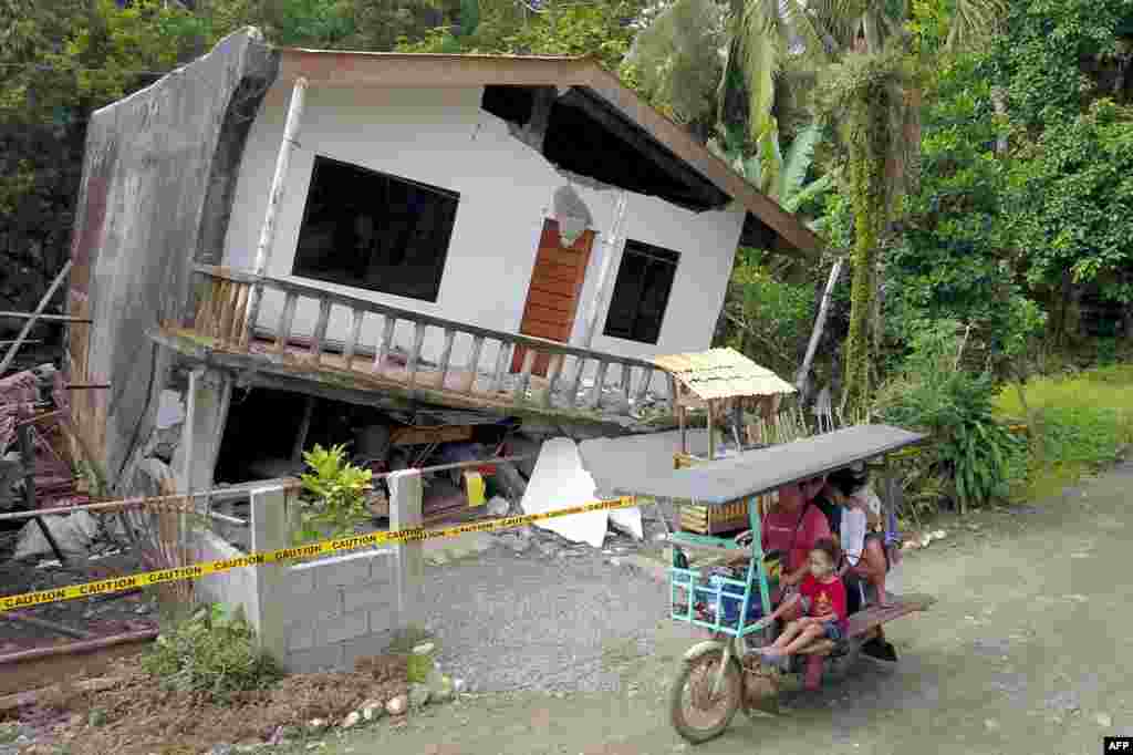 A motorist drives past a destroyed house after a large earthquake that hit Surigao City, in southern island of Mindanao, Philippines. Fifty-one people were injured and several homes, churches and other buildings damaged when an earthquake sent terrified residents of the southern Philippines fleeing their homes before dawn, police said.