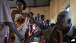 Voters wait in line to cast their vote, as others have their fingers dipped in ink to show they have done so, in an abandoned school used as a polling center in the disputed border region of Abyei, Oct. 27, 2013.
