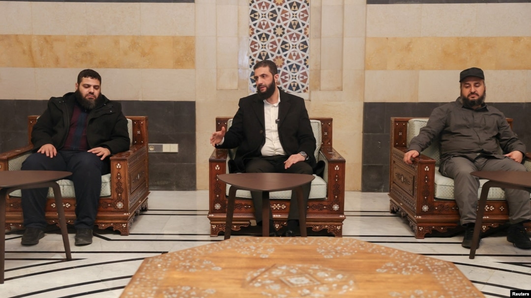 FILE - Syria's de facto leader, Ahmed al-Sharaa, center, speaks in Damascus in this handout image released Dec. 21, 2024. (Hayat Tahrir al-Sham/Handout via Reuters)