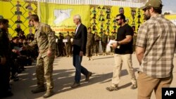 FILE - U.S. envoy William Roebuck, center, leaves the podium after speaking at a ceremony to celebrate U.S.-backed Syrian Democratic Forces defeat of Islamic State militants in Baghouz, at al-Omar Oil Field base, Syria, March 23, 2019.