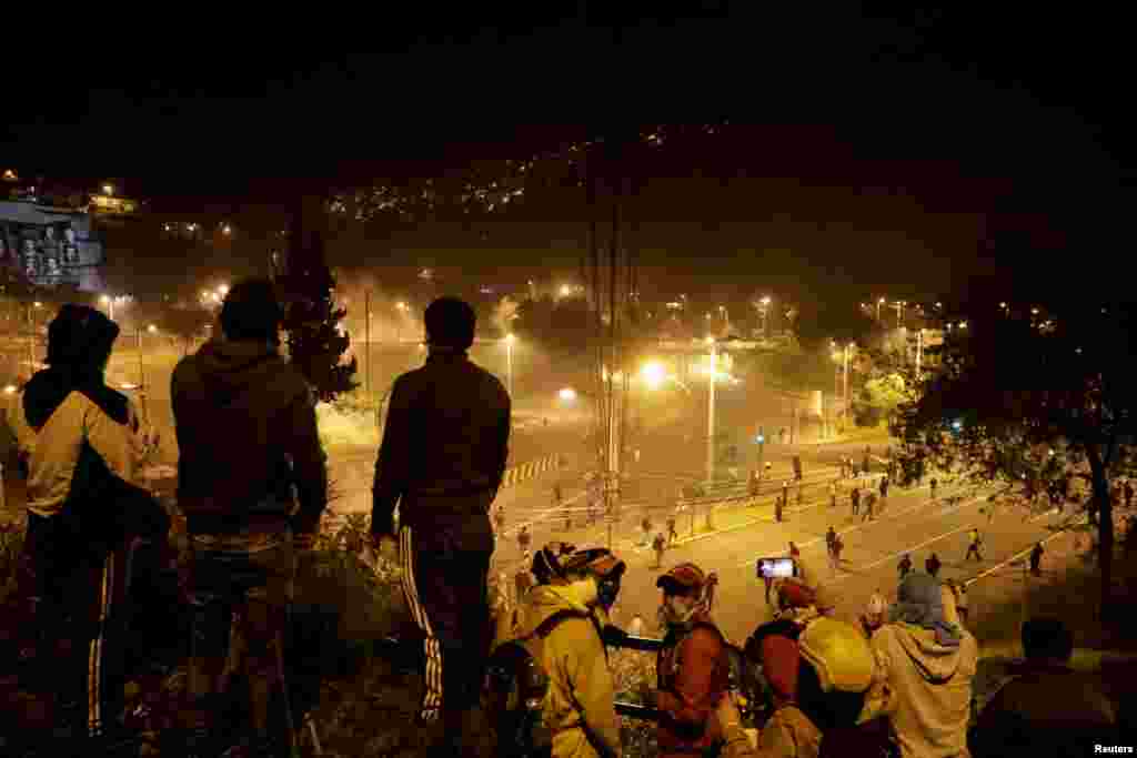Un grupo de hombres miran a los manifestantes que se dispersan en una de las calles de Quito, Ecuador. 