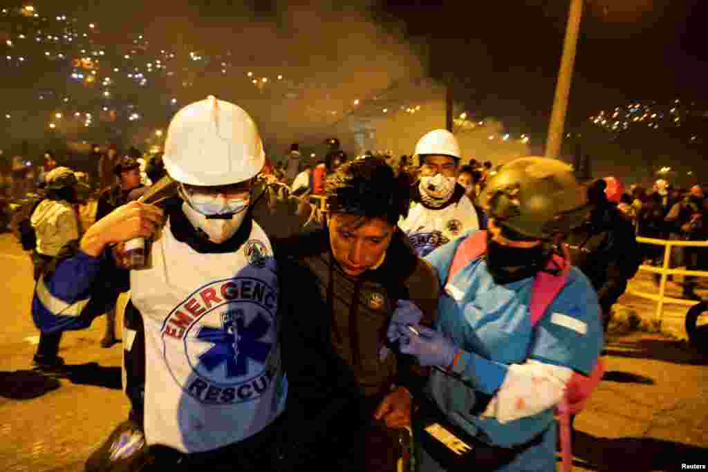 Un hombre es auxiliado por personal médico de emergencia tras ser afectado por gases lacrimógenos disparados por las fuerzas de seguridad. 