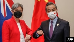 2022年7月8日，在印尼度假胜地巴厘岛努沙杜瓦举行的二十国集团外长会议期间，澳大利亚外交部长黄英贤(左)与中国外交部长王毅碰肘互致问候。