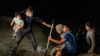 FILE - Families walk to turn themselves in to the U.S. Border Patrol after crossing the Rio Grande River into the United States from Mexico, in Roma, Texas, April 27, 2021. 