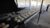FILE - A man sweeps the floor near bread at a bakery in Azaz, Syria, Jan. 26, 2020.