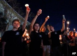 Attendees raise their candles at a candlelight vigil for the victims of the shooting at Marjory Stoneman Douglas High School, Feb. 15, 2018, in Parkland, Fla.