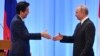 Japan's Prime Minister Shinzo Abe, left, and Russia's President Vladimir Putin reach out to shake hands during a press conference after the G-20 summit in Osaka, Japan, June 29, 2019.