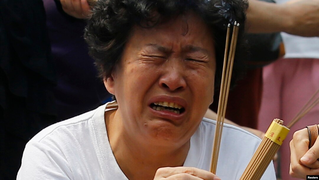 A family member of a passenger aboard the missing Malaysia Airlines flight MH370 cries as she burns incense to pray at Yonghegong Lama Temple in Beijing, June 15, 2014. 