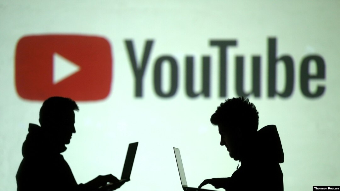 Una ilustración de siluetas de dos usuarios de aparatos móviles se ven frente a un logo de YouTube en esta ilustración de archivo.