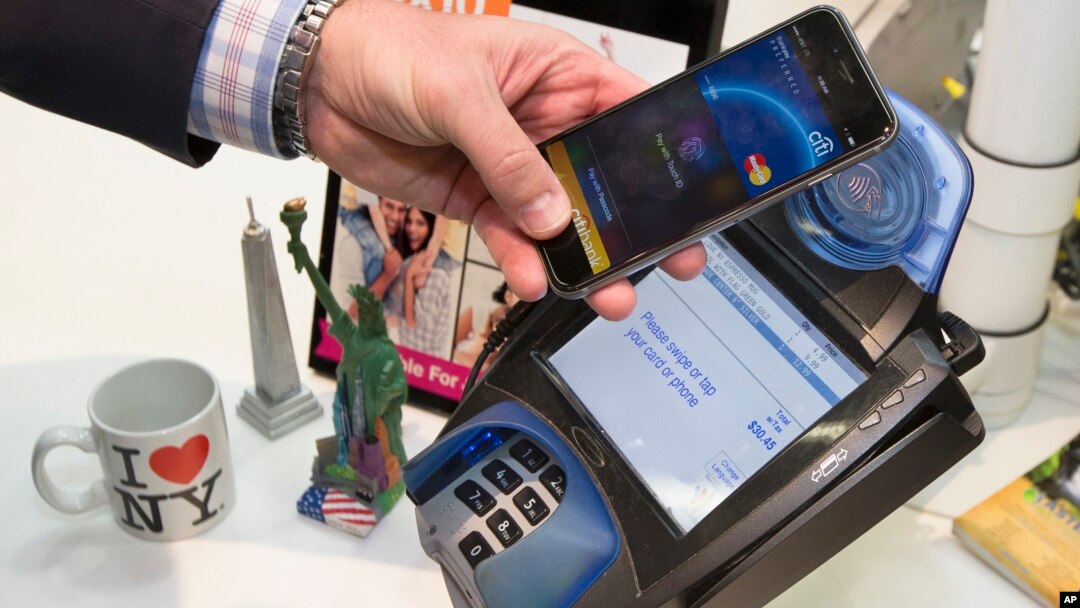 FILE - A customer makes a purchase with a MasterCard using Apple Pay on the iPhone 6 at Walgreens in Times Square in New York, Oct. 20, 2014.